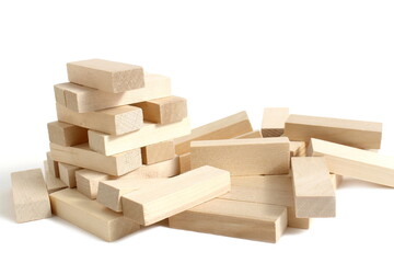 On a white background lies a collapsed tower of wooden toy blocks.	