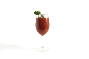 There is a glass goblet with tomato juice on a white background.	