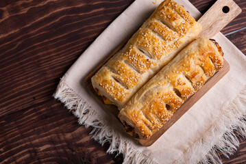 A golden puff pastry with tasty filling, sprinkled with sesame seeds.