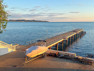 Boat docked near pier at golden hour, with calm sea and sunset reflections, ideal for travel, marine transport and coastal infrastructure themes