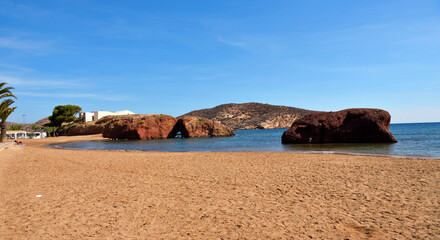 beach in Mazarrón, Spain, with red rocks the beach is characterized by fine golden sand and...