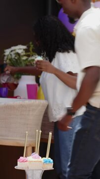 Vertical video: Birthday party sparking three-generation family sharing cupcakes and hugs on patio