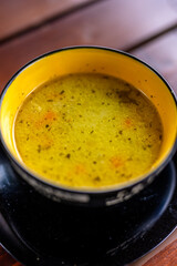 Bowl of hot soup served on a rustic wooden table at the terrace of a mountain restaurant