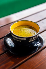 Bowl of hot soup served on a rustic wooden table at the terrace of a mountain restaurant