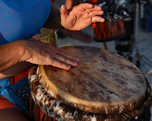 A man's hand hovers over the head of a drum during a performance at the beach