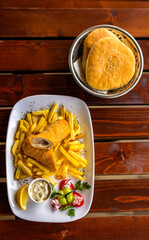 Breaded rolled meat served with crispy French fries on a white plate.