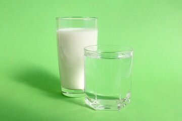 On a green background there is a glass of water and milk.
