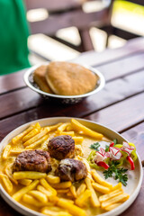 Juicy meatballs served with golden French fries on a white plate. A hearty, classic comfort meal...