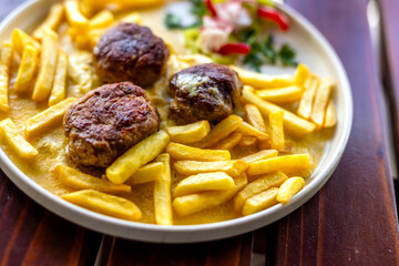 Juicy meatballs served with golden French fries on a white plate. A hearty, classic comfort meal...