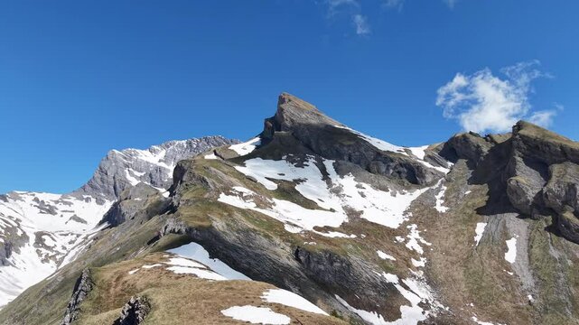 Paysage alpin spectaculaire sous un ciel bleu &eacute;clatant. D&rsquo;imposants sommets rocheux et enneig&eacute;s se dressent au c&oelig;ur des montagnes, offrant une vue majestueuse et sauvage. Vid&eacute;o drone 4k 60fps