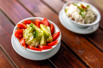 Fresh cucumber and tomato salad served in a bowl on a wooden table.