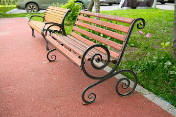 A beautiful wooden decorative benches in a city park. Empty modern wooden benches.