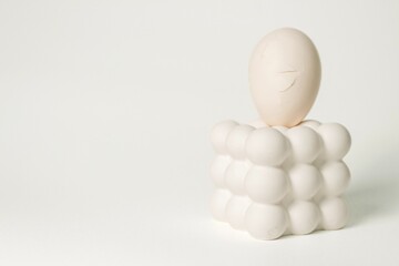 Cracked white egg placed on a modern bubble-style egg holder on isolated white background. 