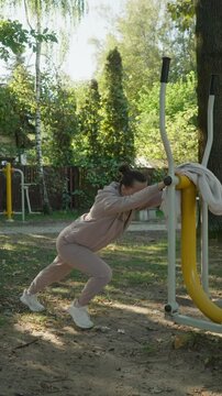 A woman performs a standing calf stretch against outdoor gym equipment. This cool-down exercise improves leg flexibility and helps with muscle recovery and injury prevention.