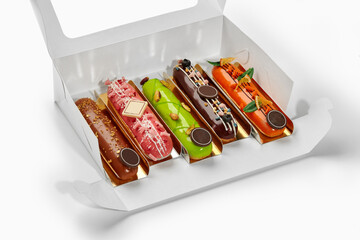 Set of colorful eclairs with creative toppings in a white gift box