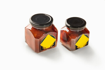 Two jars of baba al rhum showing preserved cherries in rum syrup on white background