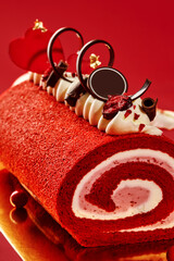 Red velvet roll cake decorated with whipped cream, chocolate and cherries for valentine's day