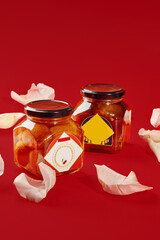 Two luxardo baba al maraschino jars decorated with rose petals on red background