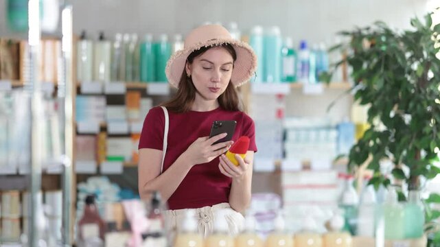 Selective young woman in summer clothes scanning barcode on sunscreen in chemist's shop. High quality 4k footage