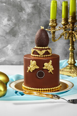 Luxurious chocolate easter cake decorated with golden angels and chocolate egg