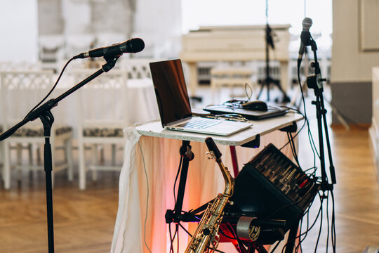 Elegant music setup with laptop, saxophone, and microphones prepared for a live performance in a sophisticated event venue wedding DJ musician