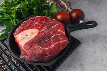 Raw pieces of ossobuco steak with spices in the entourage before cooking, close-up. Fresh raw beef steak with bone or ossobuco with salt, spices and herbs