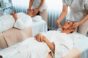 Obraz premium Caucasian couple enjoying relaxing anti-stress head massage and pampering facial beauty skin recreation leisure in dayspa modern light ambient at luxury resort or hotel spa salon. Quiescent