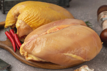 Chicken breasts with and without skin. Raw chicken breast fillets with rosemary and spices on a wooden cutting board. Close-up