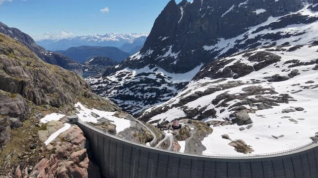 Vue a&eacute;rienne spectaculaire d&rsquo;un barrage en arc au c&oelig;ur des Alpes, entour&eacute; de neige et de montagnes rocheuses. Vid&eacute;o drone 4k 60fps