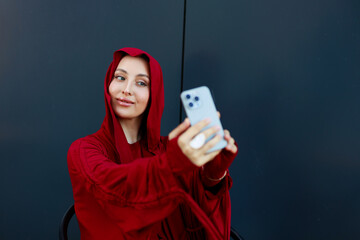 stylish muslim woman in red headscarf taking selfie	
