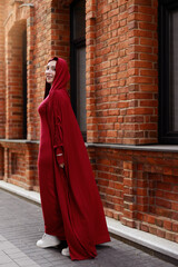 beautiful islamic woman in national dress walking against brick wall