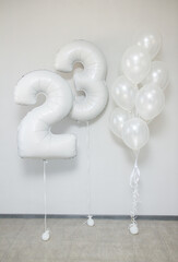 white pearlescent balloons with helium in a bunch and white foil numbers 23