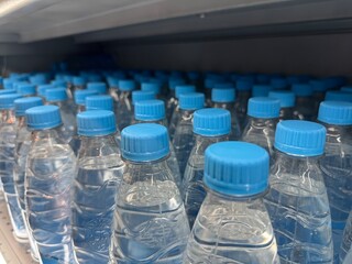 row of clear plastic water bottles with blue caps neatly aligned on a store shelf