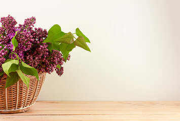 basket with lilac flowers on wooden boards.