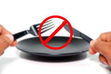 Empty plate with cutlery set holding hands with Alert or warning sign on foreground blurry background , No food or no eating concept photography 