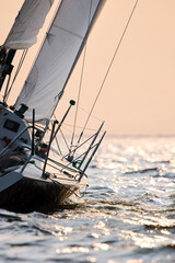 Sailing regatta in the Gulf of Finland at sunset, sailing yacht competing in a race, splashing water from under the boat, teamwork, board the boat