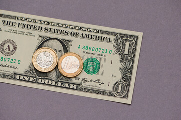Unique collection of currency featuring a one dollar bill and foreign coins on a purple background