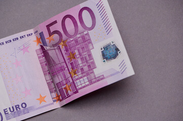 Close-up view of a 500 euro banknote showcasing its intricate design and vibrant colors on a gray background