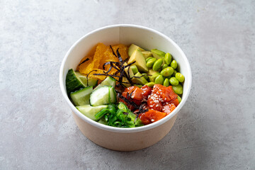 Vibrant poke bowl filled with diced salmon, avocado, cucumber, orange segments, edamame, and seaweed, creating an appetizing medley of healthy ingredients