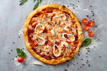 A delicious pizza featuring a crispy crust, vibrant red peppers, fresh tomatoes, and savory chicken, sits on a rustic countertop sprinkled with flour. Aromas of herbs fill the air