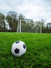 Classic style soccer or football on neatly cut green grass with small training goal posts in the...