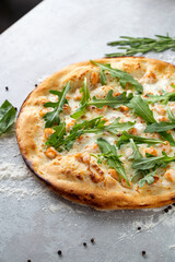 Golden crust pizza baked to perfection sits on a textured surface, adorned with vibrant greens and succulent shrimp, promising a delicious culinary delight