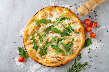 Savor the aroma of freshly baked artisan pizza with a golden crust, topped with vibrant arugula, cherry tomatoes, and sprinkled herbs, resting on a kitchen surface dusted with flour