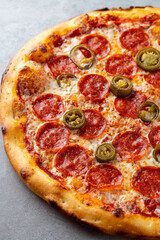 A freshly baked pizza topped with spicy pepperoni and zesty jalapenos sits on a rustic surface, inviting pizza lovers to indulge in its deliciousness, perfect for sharing with friends