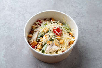A vibrant bowl of mixed greens topped with croutons, diced tomatoes, and a drizzle of creamy dressing sits invitingly on a simple surface. Perfect for a light lunch anytime