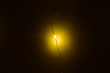 A single yellow light illuminates a dark, unlit space.