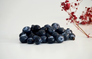 Close-up of Fresh Blueberries on a White Background with Flowers