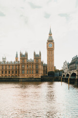 Obraz premium Iconic view of Big Ben with a red double-decker bus and the London Eye in the background on a cloudy day in London.