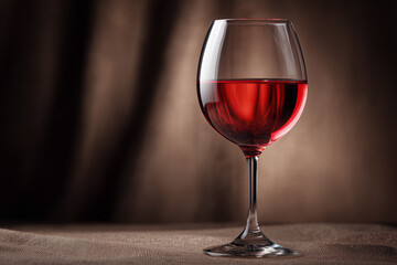 Red wine glass on fabric background with soft lighting