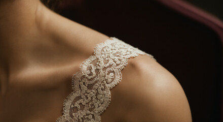 Close-up of a shoulder with Lace strap against dark background
